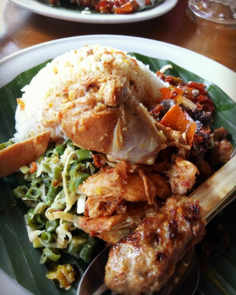 makanan khas bali bernama nasi campur ayam disajikan dengan daun pisang